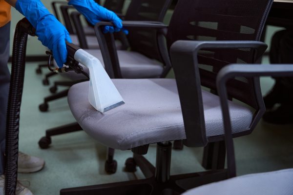 Certified cleaning specialist using upholstery vacuum-cleaner for chairs