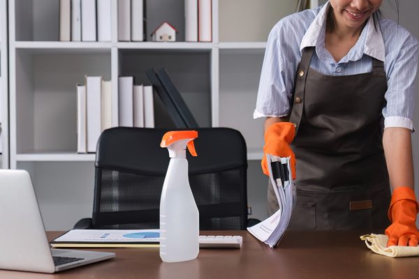 Young woman uses a cleaning cloth to disinfect the computer and equipment on the office table